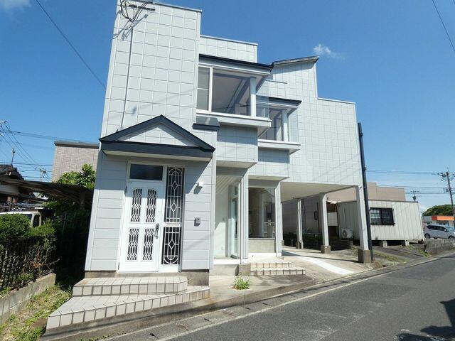 This unique home features an unusual shape and layout, accommodating two cars parked in a row